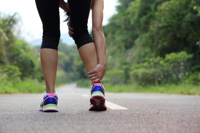 Female runner holding her ankle in pain